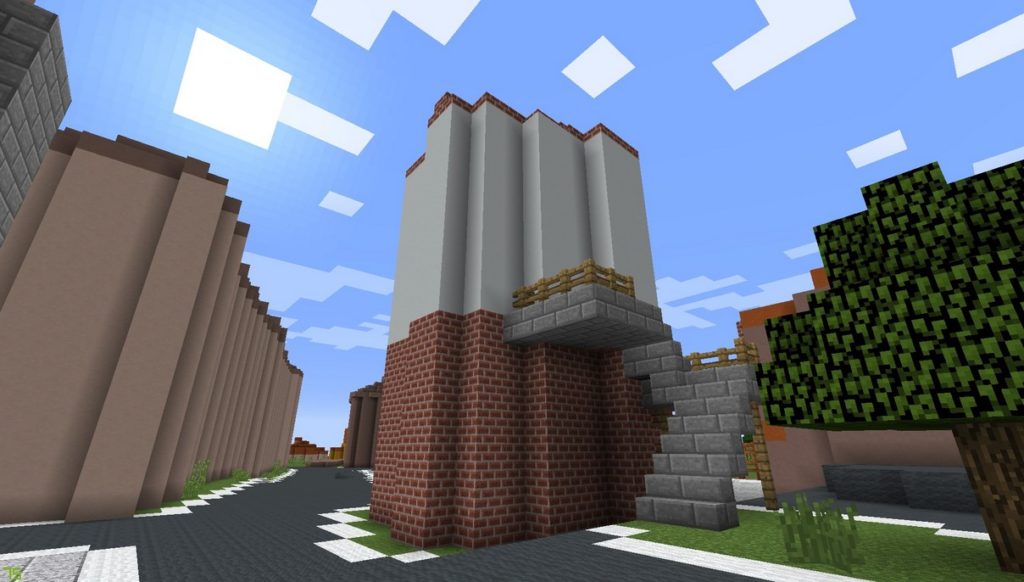 Gdańsk. The White Tower. Minecraft visualisation. The photograph features a historic medieval tower constructed from brick blocks at the base and grey blocks in its upper parts. On the right side of the tower some stone steps are added with a wooden balustrade and a ladder. On the left side there is a road constructed from dark grey blocks. 