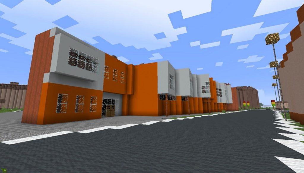 Gdańsk. The Primary School no. 67. Minecraft visualisation. The photograph presents a building constructed from white and orange blocks. The entrance is constructed from two wooden doors and windows. On the ground floor and the first floor numerous windows can be seen. In front of the building there is a dark grey road.